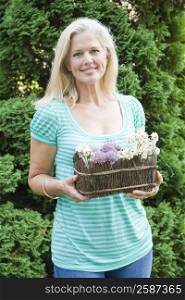 Portrait of a mature woman holding hanging basket and smiling