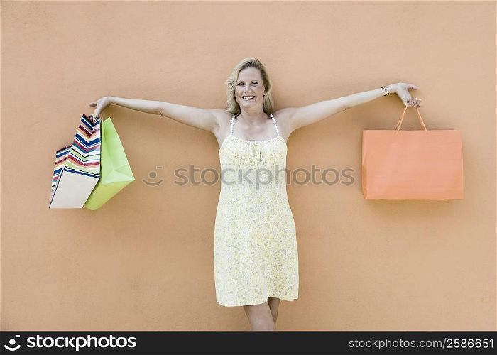 Portrait of a mature woman holding shopping bags with her arms outstretched