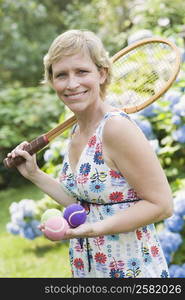 Portrait of a mature woman holding tennis balls and a tennis racket