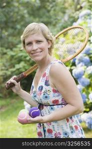 Portrait of a mature woman holding tennis balls and a tennis racket