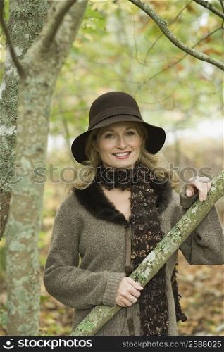 Portrait of a mature woman holding the branch of a tree and smiling
