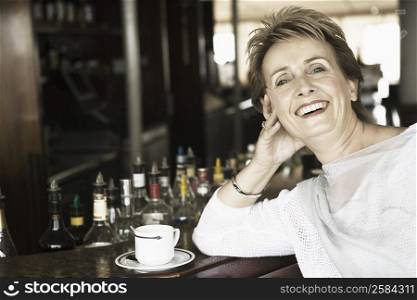 Portrait of a mature woman leaning against a bar counter and smiling