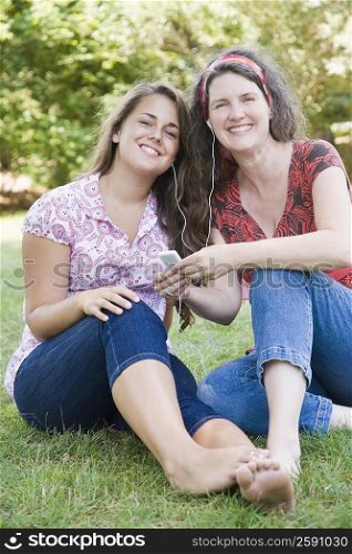 Portrait of a mature woman listening to an MP3 player with her daughter and smiling