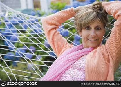 Portrait of a mature woman lying in a hammock with her hands behind her head