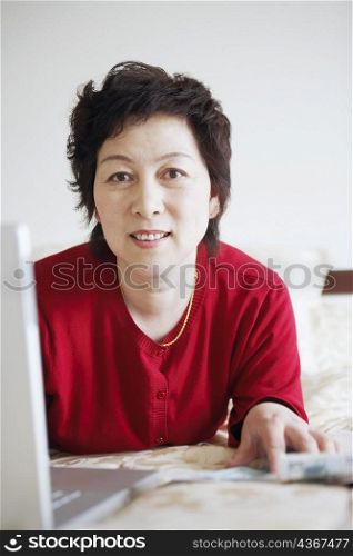 Portrait of a mature woman lying in front of a laptop