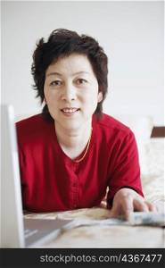 Portrait of a mature woman lying in front of a laptop