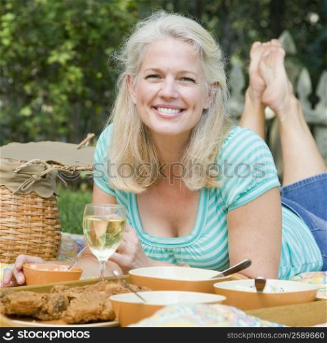 Portrait of a mature woman lying on a picnic blanket and smiling