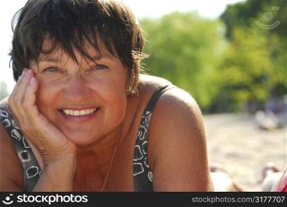 Portrait of a mature woman lying on a sandy beach