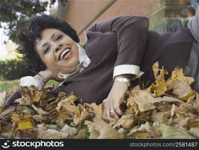 Portrait of a mature woman lying on fallen leaves and smiling
