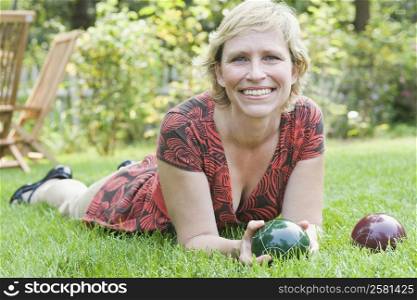 Portrait of a mature woman lying on grass and holding a croquet ball