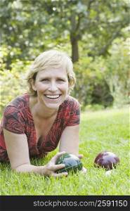 Portrait of a mature woman lying on grass and holding a croquet ball