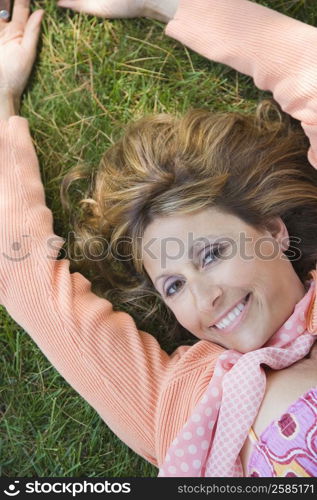 Portrait of a mature woman lying on grass and smiling