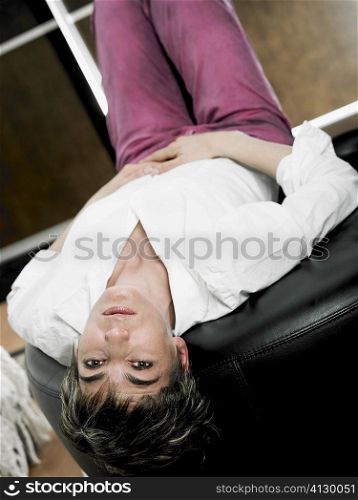 Portrait of a mature woman lying on her back on a stool