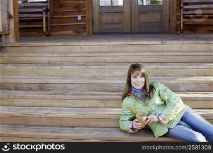 Portrait of a mature woman lying on steps and holding a cup