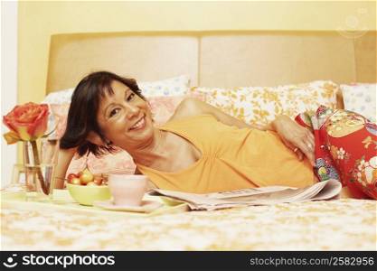 Portrait of a mature woman lying on the bed and smiling