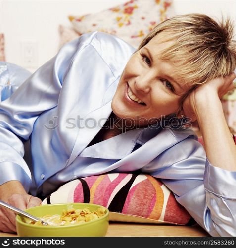 Portrait of a mature woman lying on the floor with a bowl of corn flakes