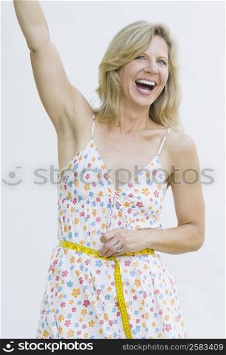 Portrait of a mature woman measuring her waist with a tape measure