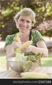 Portrait of a mature woman peeling a corn and smiling