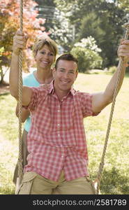 Portrait of a mature woman pushing a mature man on a rope swing