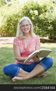 Portrait of a mature woman reading a book in a park and smiling