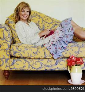 Portrait of a mature woman reclining on a couch and knitting
