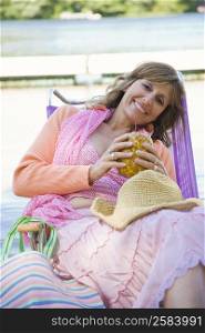 Portrait of a mature woman reclining on a deck chair and holding a pineapple