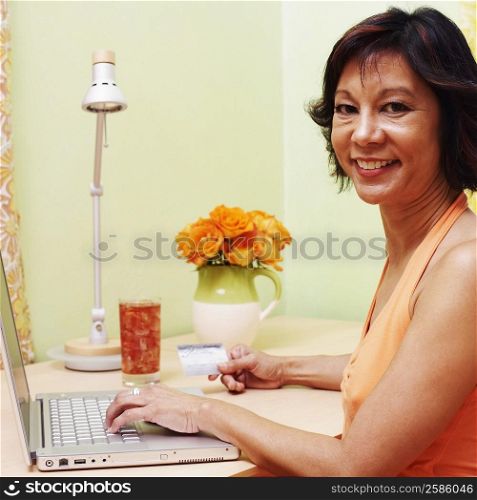 Portrait of a mature woman shopping online with a credit card