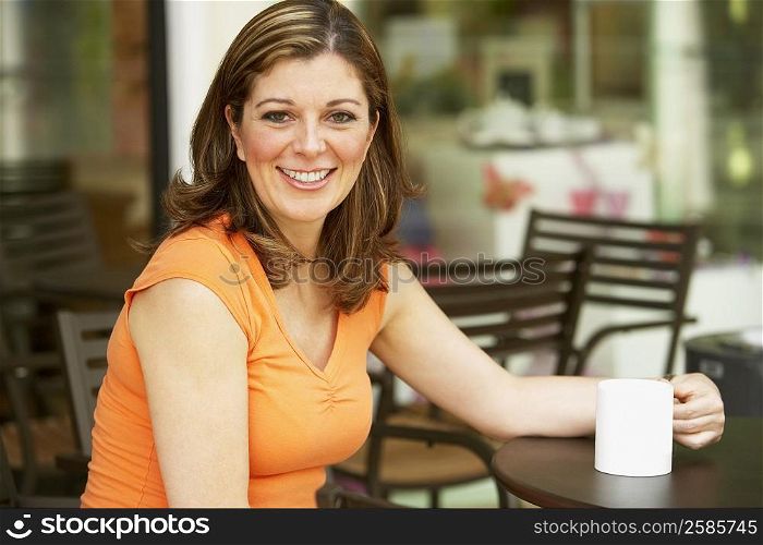 Portrait of a mature woman sitting at a table and holding a cup