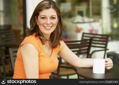 Portrait of a mature woman sitting at a table and holding a cup