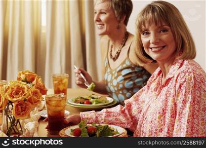 Portrait of a mature woman sitting at the dining table with her friend and smiling