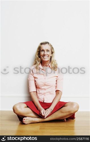 Portrait of a mature woman sitting cross-legged on the floor and smiling