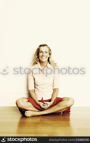 Portrait of a mature woman sitting cross-legged on the floor and smiling