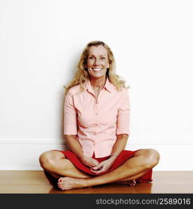 Portrait of a mature woman sitting cross-legged on the floor and smiling