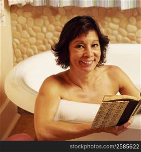 Portrait of a mature woman sitting in a bathtub and holding a book