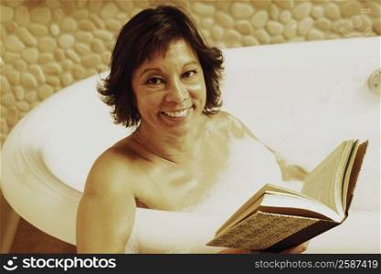 Portrait of a mature woman sitting in a bathtub and holding a book