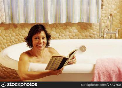 Portrait of a mature woman sitting in a bathtub holding a book