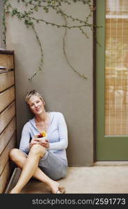 Portrait of a mature woman sitting in the corner and holding a bowl