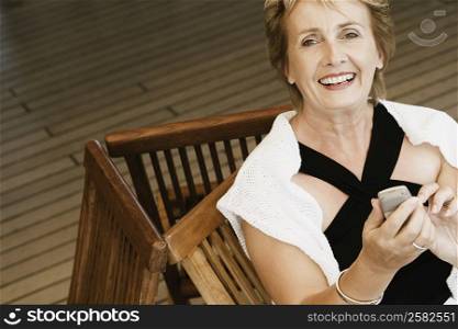 Portrait of a mature woman sitting on a chair and holding a mobile phone
