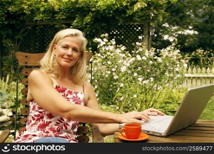 Portrait of a mature woman sitting on a chair and using a laptop