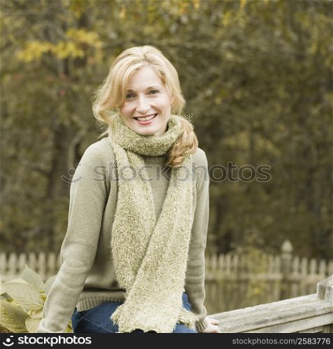 Portrait of a mature woman sitting on a fence and smiling
