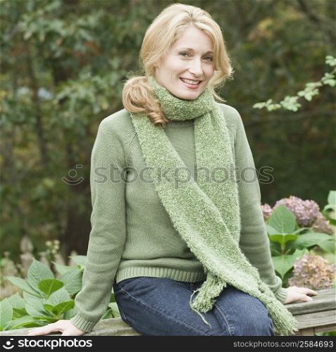 Portrait of a mature woman sitting on a fence and smiling
