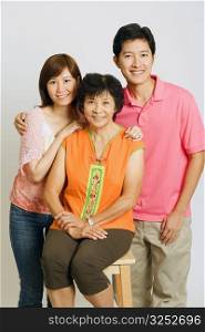Portrait of a mature woman sitting on a stool and a young couple standing beside her
