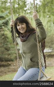 Portrait of a mature woman sitting on a swing and smiling