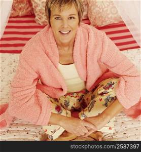 Portrait of a mature woman sitting on the bed and smiling