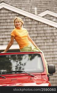 Portrait of a mature woman sitting on the top of a sports utility vehicle