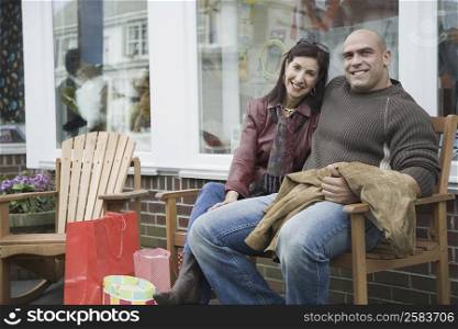 Portrait of a mature woman sitting with a mid adult man on a bench and smiling