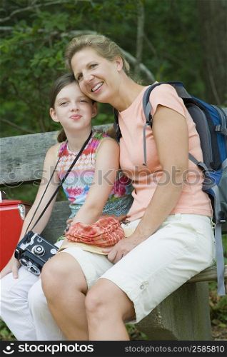 Portrait of a mature woman sitting with her daughter on a bench