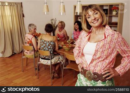 Portrait of a mature woman smiling and her friends sitting at the dining table in the background