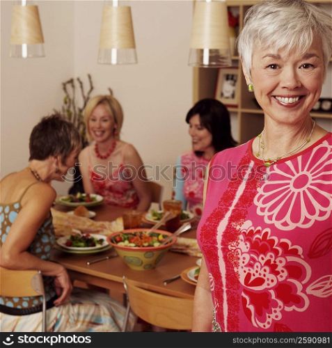 Portrait of a mature woman smiling and her friends sitting at the dining table in the background