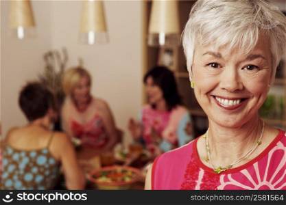 Portrait of a mature woman smiling and her friends sitting behind her